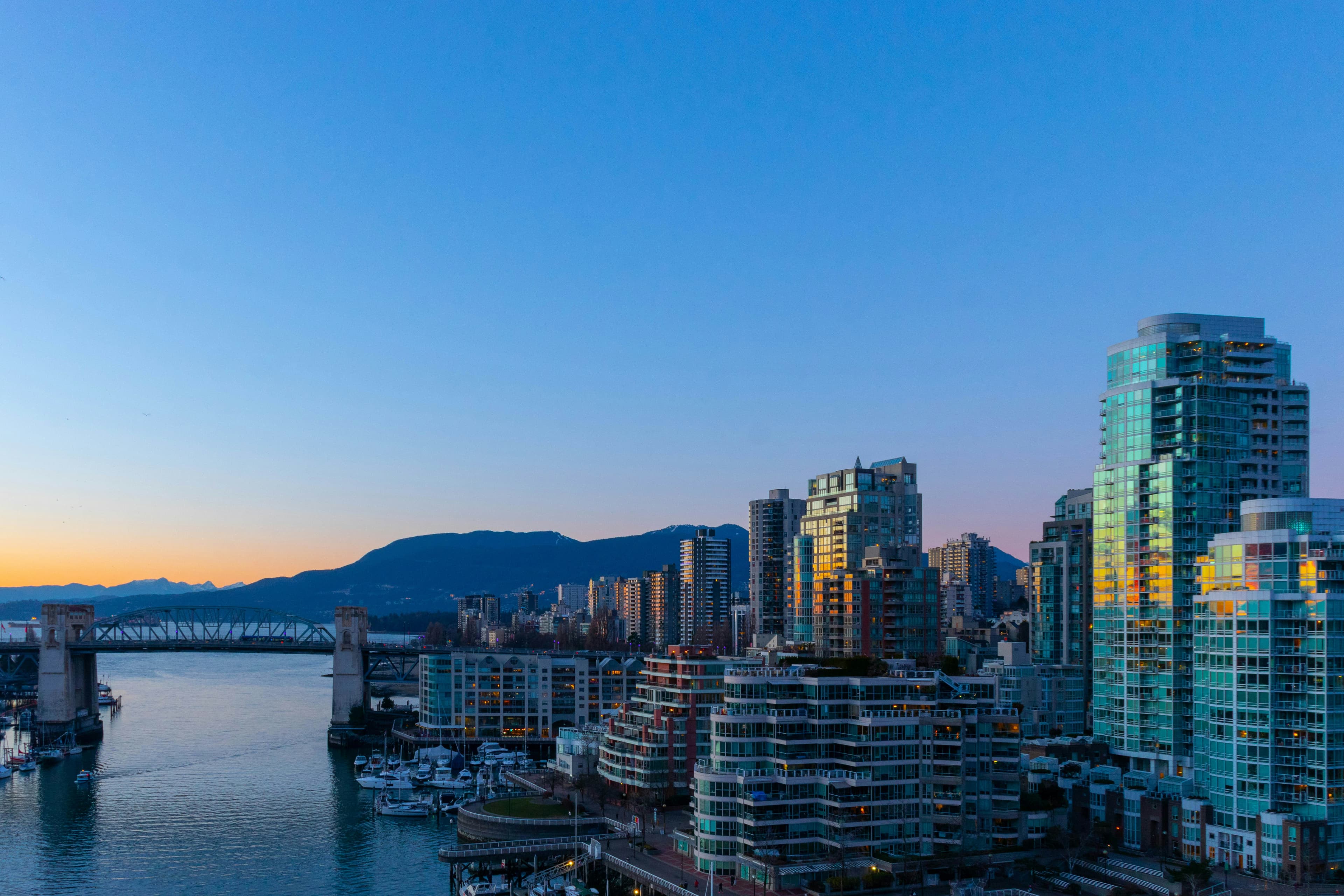Burrard Bridge and the West End condominium towers at dusk, the sky fading from blue to a warm horizon.